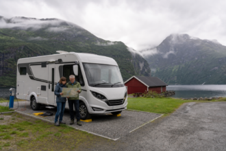 Wohnmobilreisende planen auf einem norwegischen Fjord-Campingplatz ihre Route und richten das Fahrzeug aus [Bildinhalt mit KI erstellt]