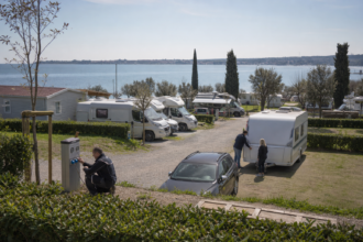 Mitarbeiter bereiten einen Campingstellplatz am Gardasee für anreisende Gäste vor [Bildinhalt mit KI erstellt]