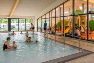 Familien nutzen Hallenbad und Indoorspielplatz eines europäischen Campingplatzes [Bildinhalt mit KI erstellt]