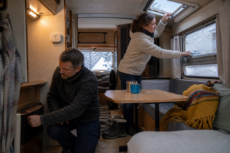 Camper prüfen Heizung und Lüftung und entfernen Kondenswasser im winterlichen Wohnwagen [Bildinhalt mit KI erstellt]