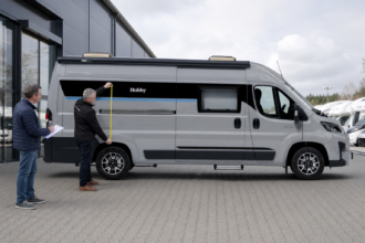 Fachberater vermessen mit einem Interessenten die Außenmaße des Hobby ONTOUR VAN 2025 [Bildinhalt mit Ki bearbeitet]