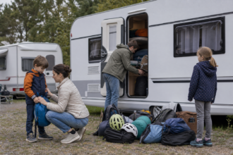 Familie verstaut Reisegepäck und Kinderausrüstung in einem praktischen Wohnwagen [Bildinhalt mit Ki bearbeitet]
