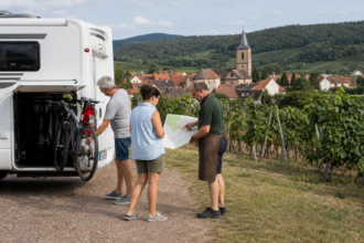 Wohnmobilreisende planen mit einem Winzer eine Fahrradtour durch die Weinberge der Pfalz [Bildinhalt mit KI erstellt]