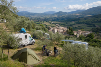 Campingplatz zwischen Olivenbäumen mit Blick auf ein italienisches Bergdorf [Bildinhalt mit KI erstellt]