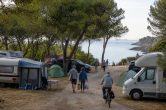 Gut besuchter europäischer Küstencampingplatz mit Zelten und Wohnmobilen [Bildinhalt mit KI erstellt]